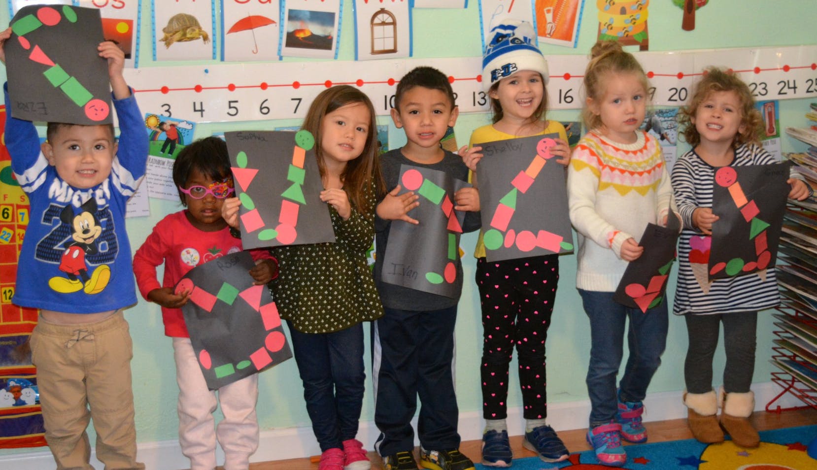 Group of children holding up artwork in a classroom