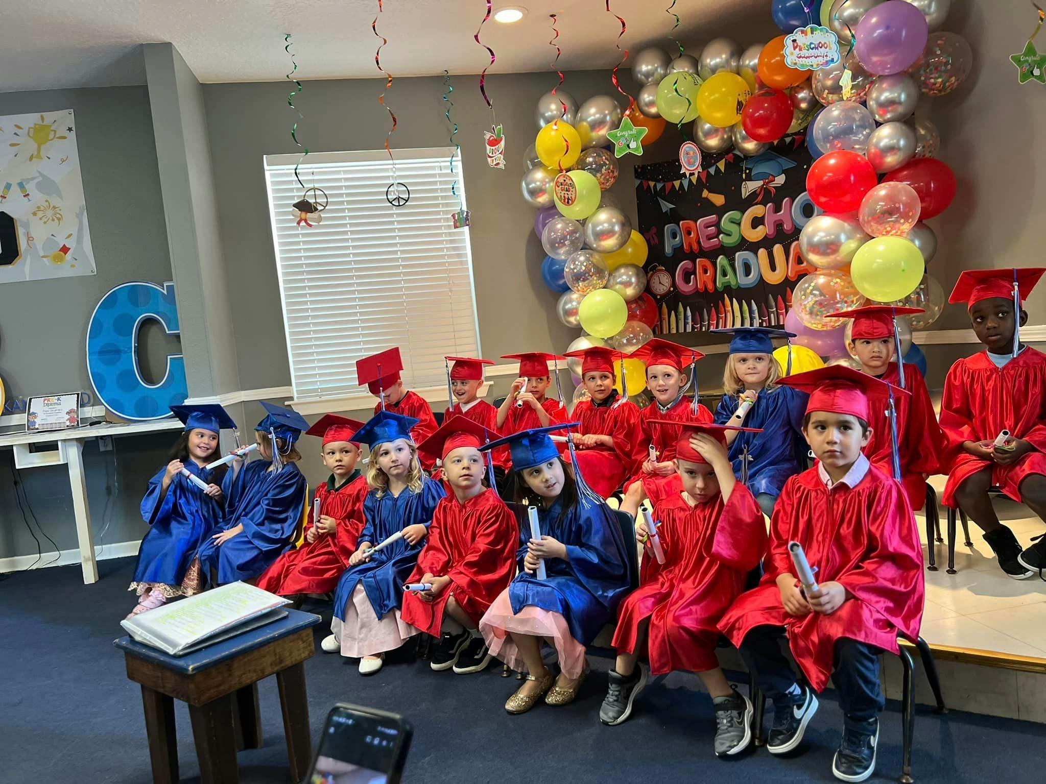 Children in graduation caps and gowns sitting in rows