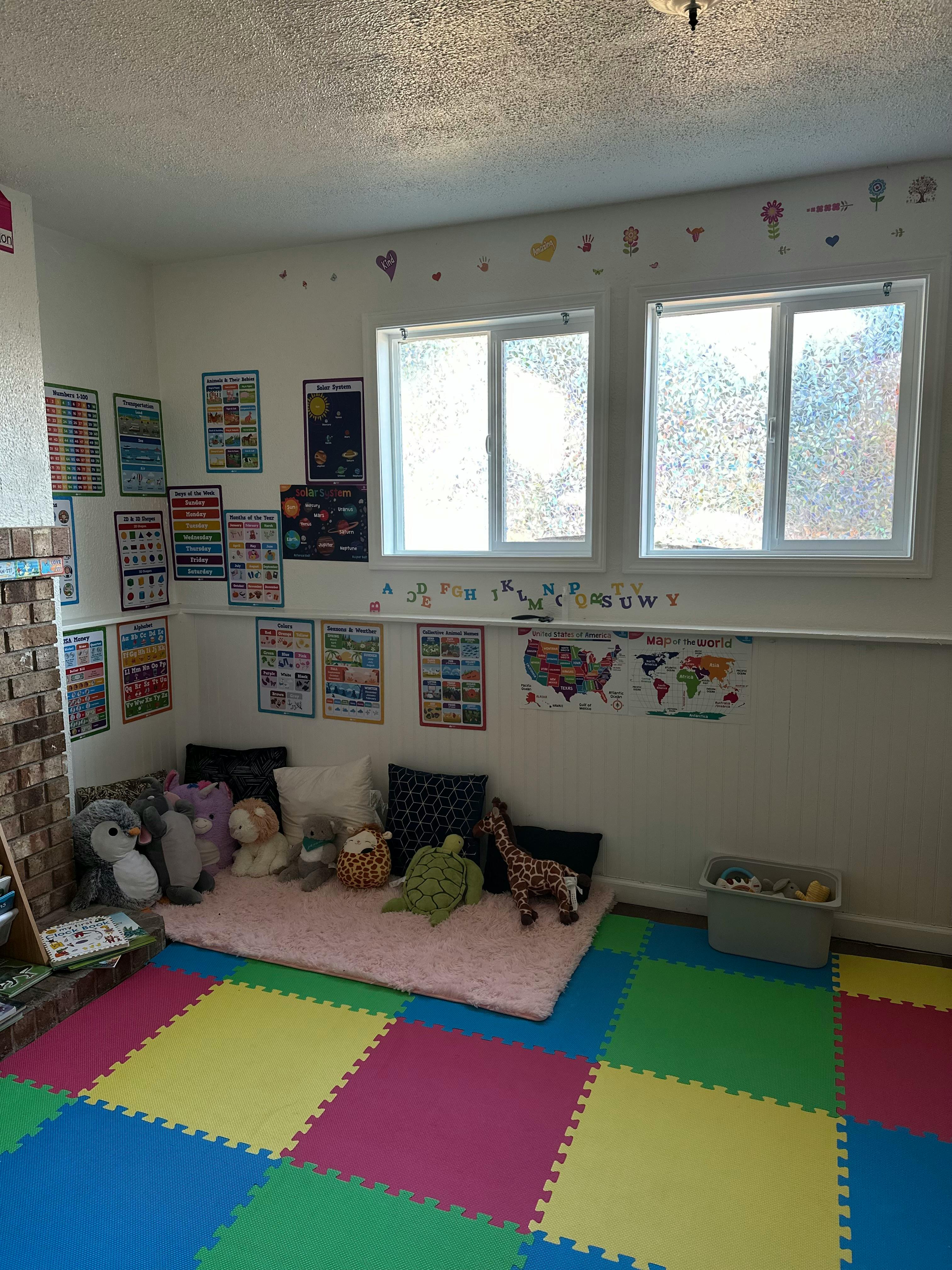 Childrens play area with educational posters and plush toys on a floor mat