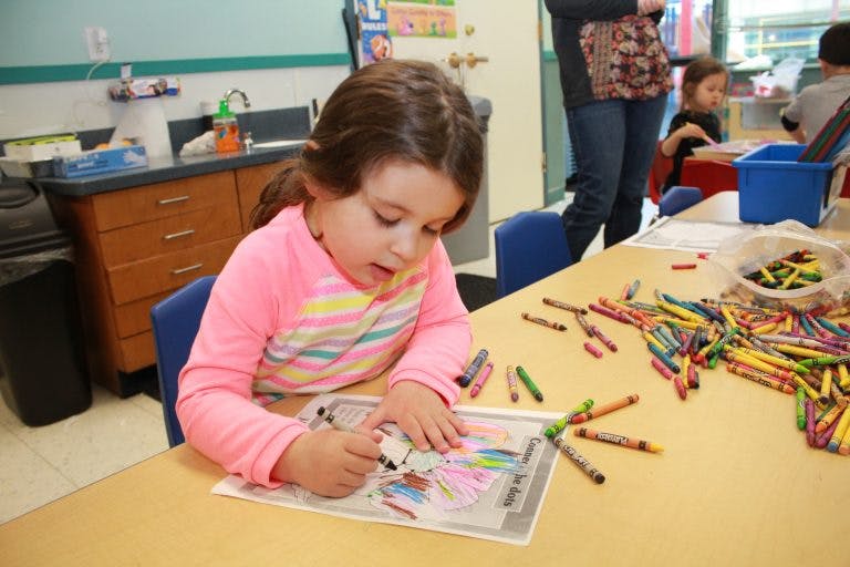 Child coloring at a table in a classroom