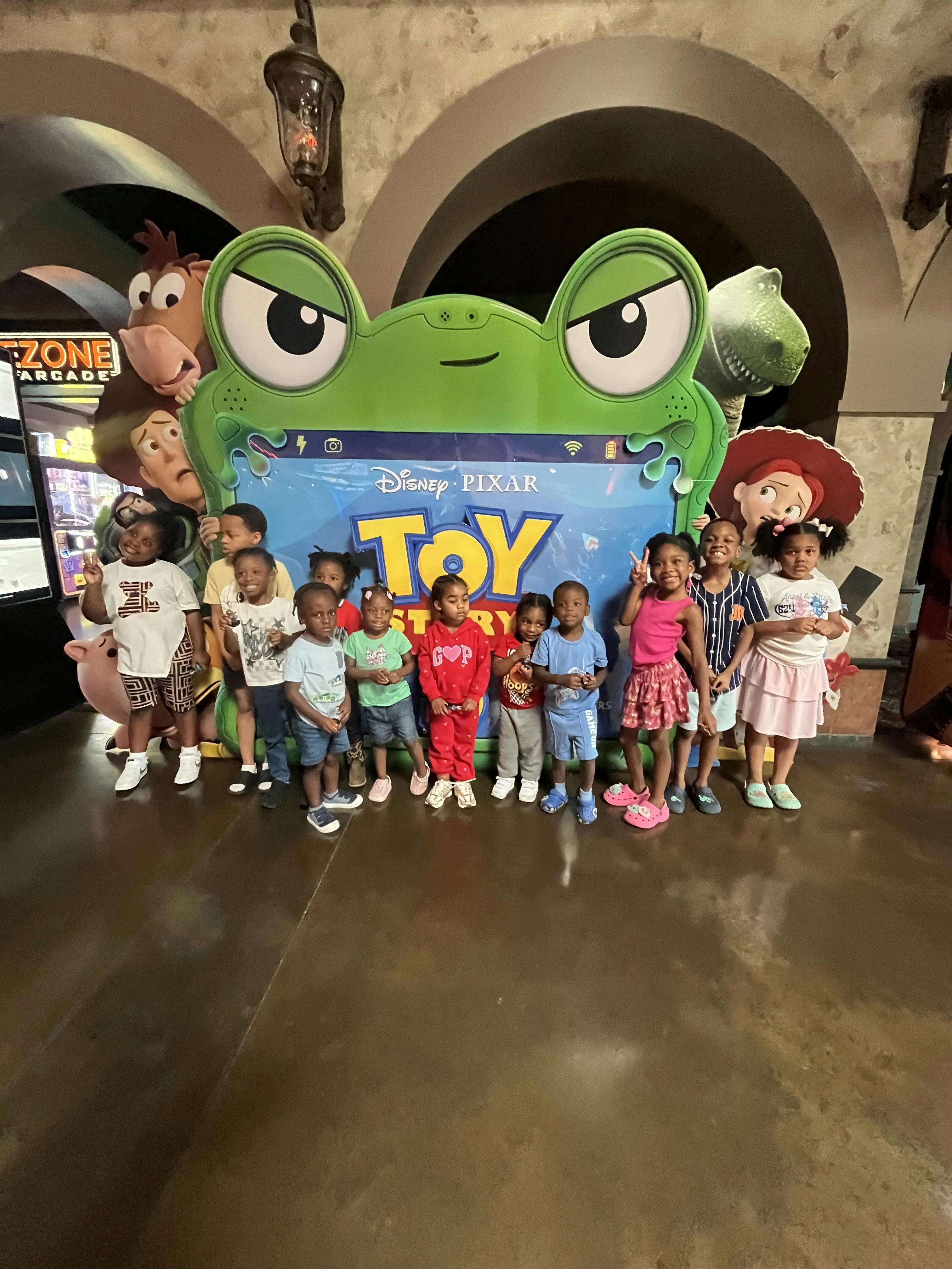 Group of children posing in front of a Toy Story sign
