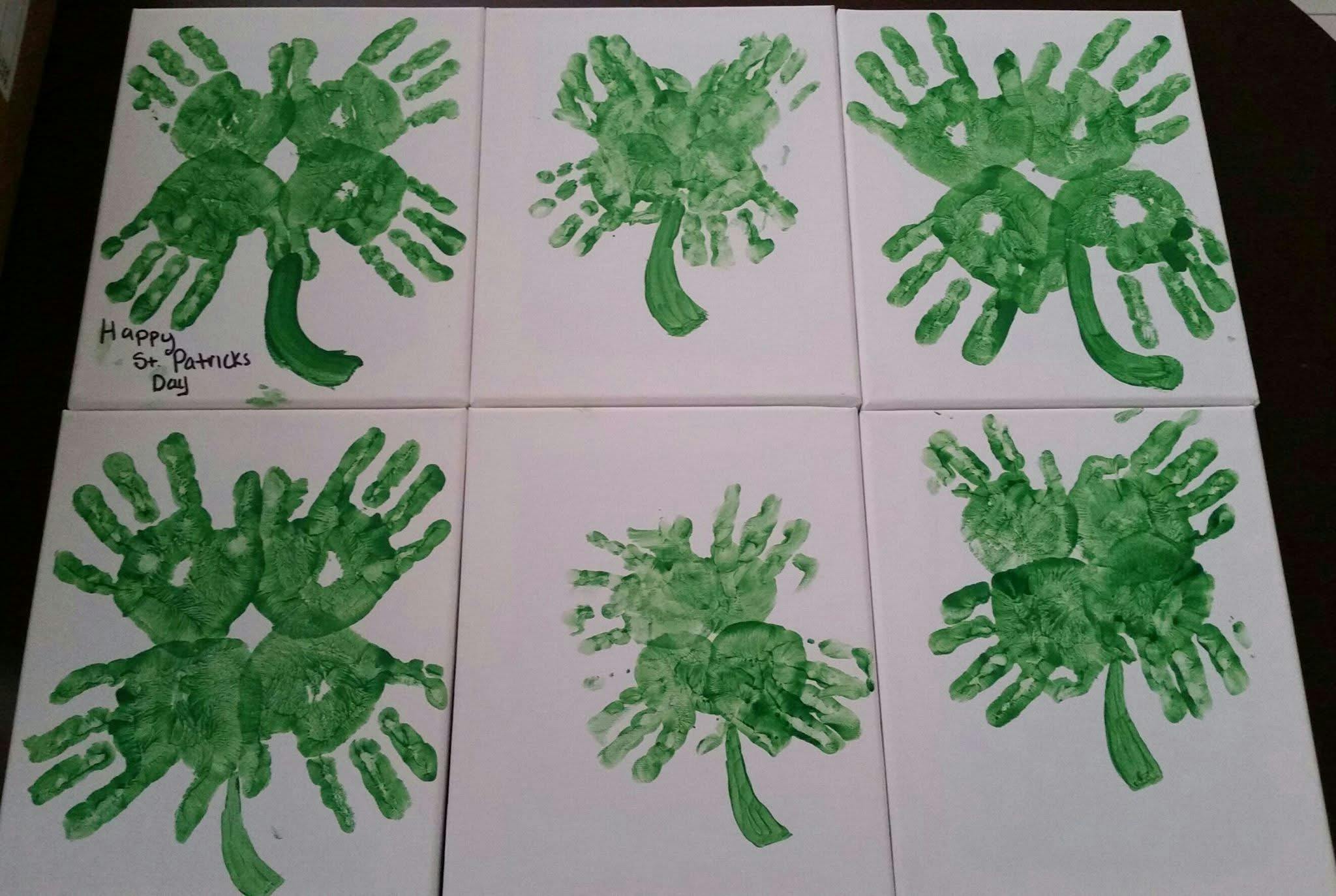 Six pieces of paper with green handprint shamrocks