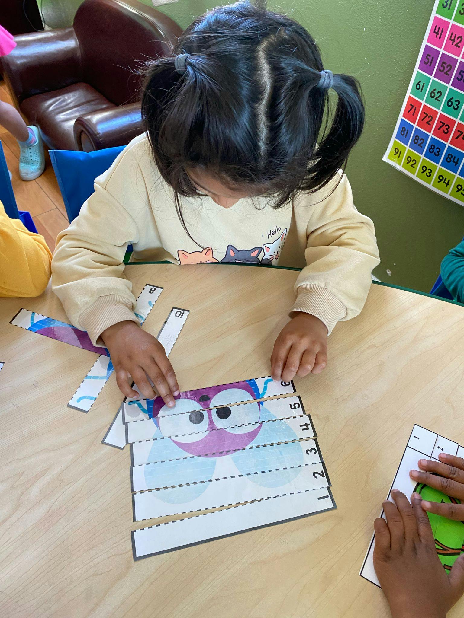 Child assembling a paper puzzle on a wooden table