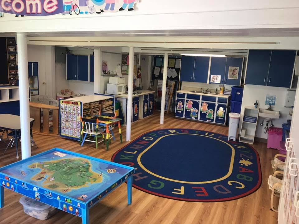 Playroom with a blue rug, small tables, and blue cabinets