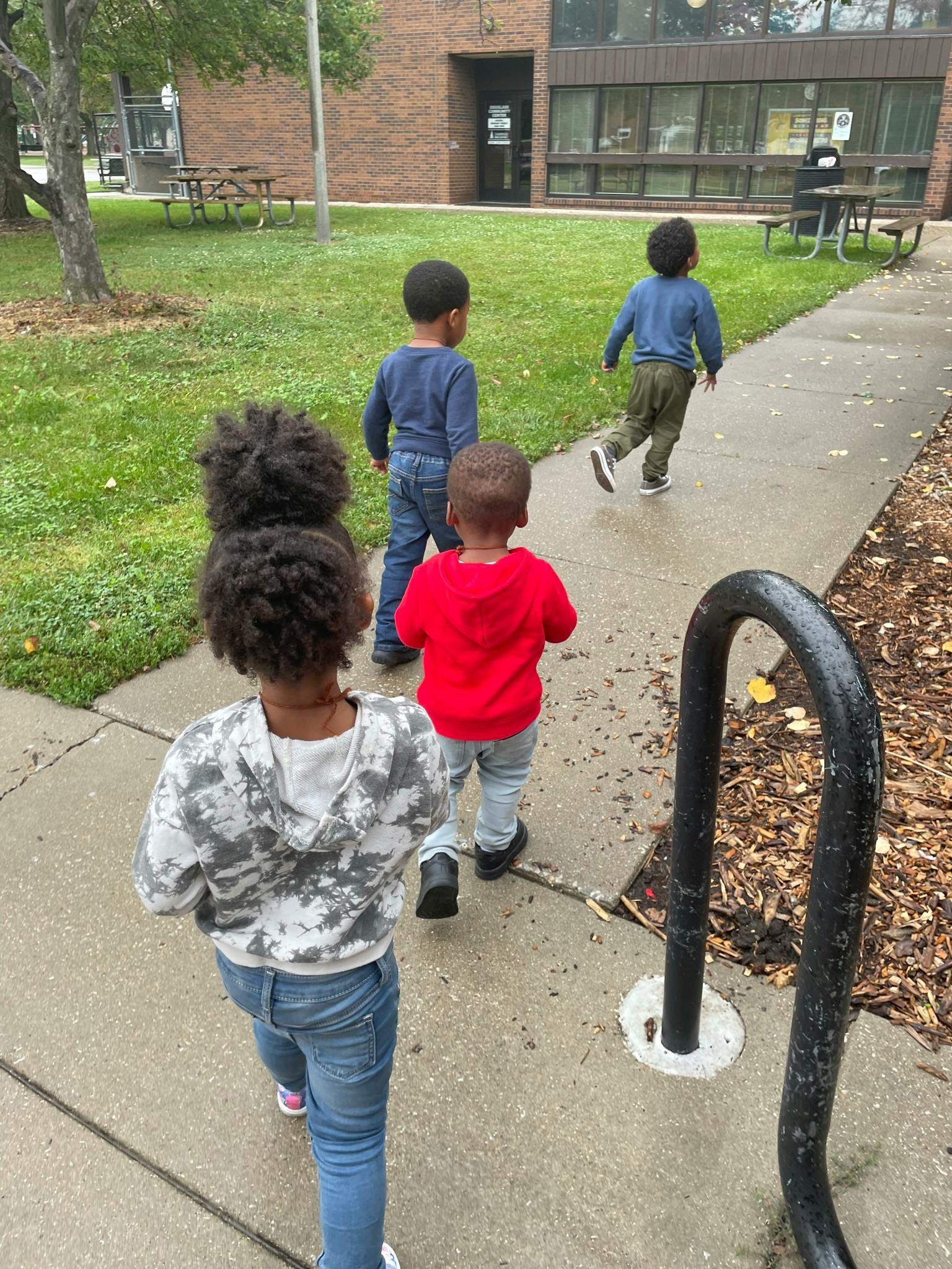 Four children walking on a sidewalk
