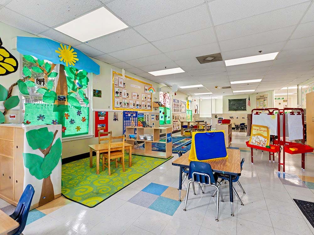 Empty colorful preschool classroom with small tables and chairs
