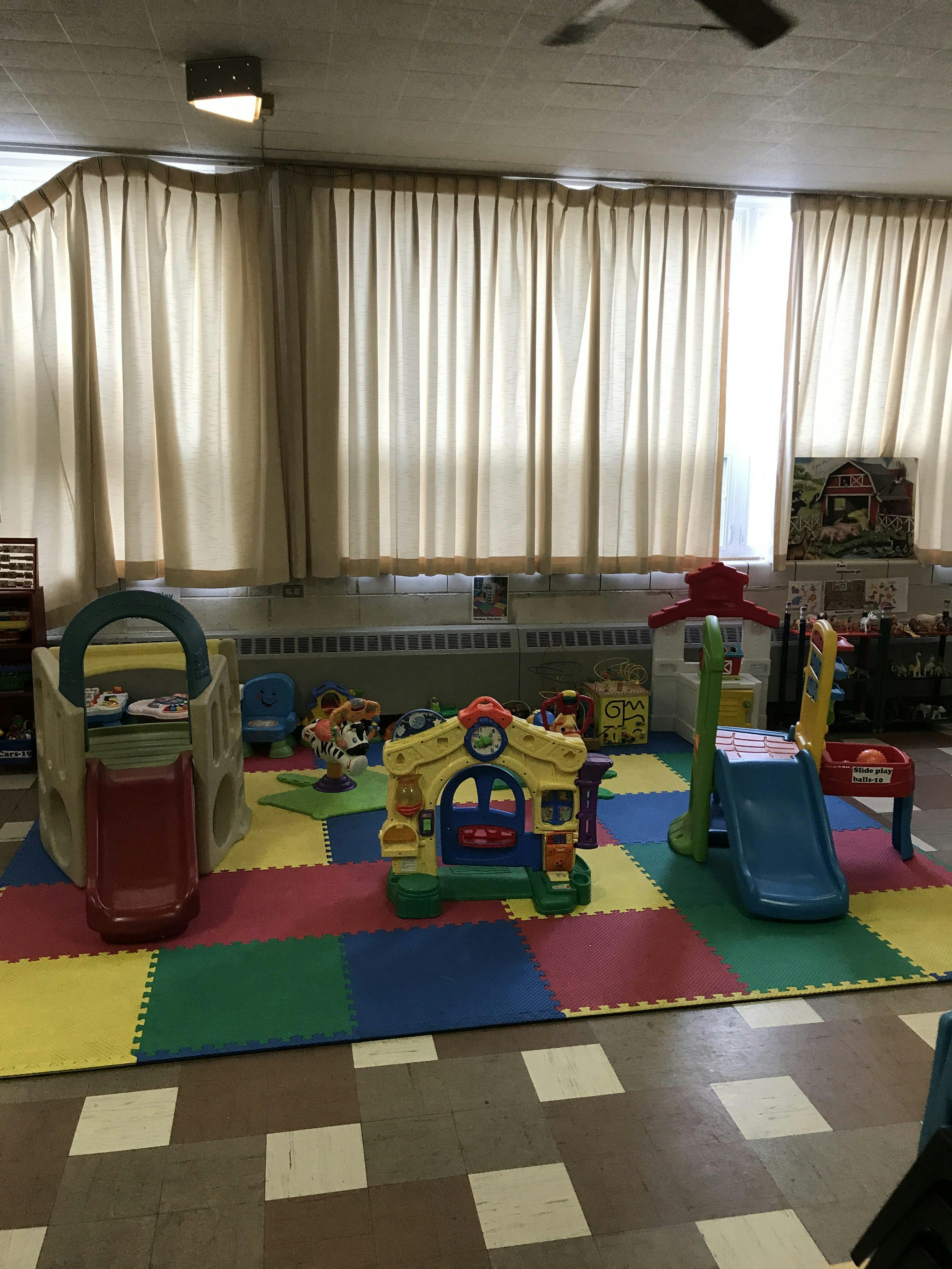Indoor play area with colorful mats and plastic play structures