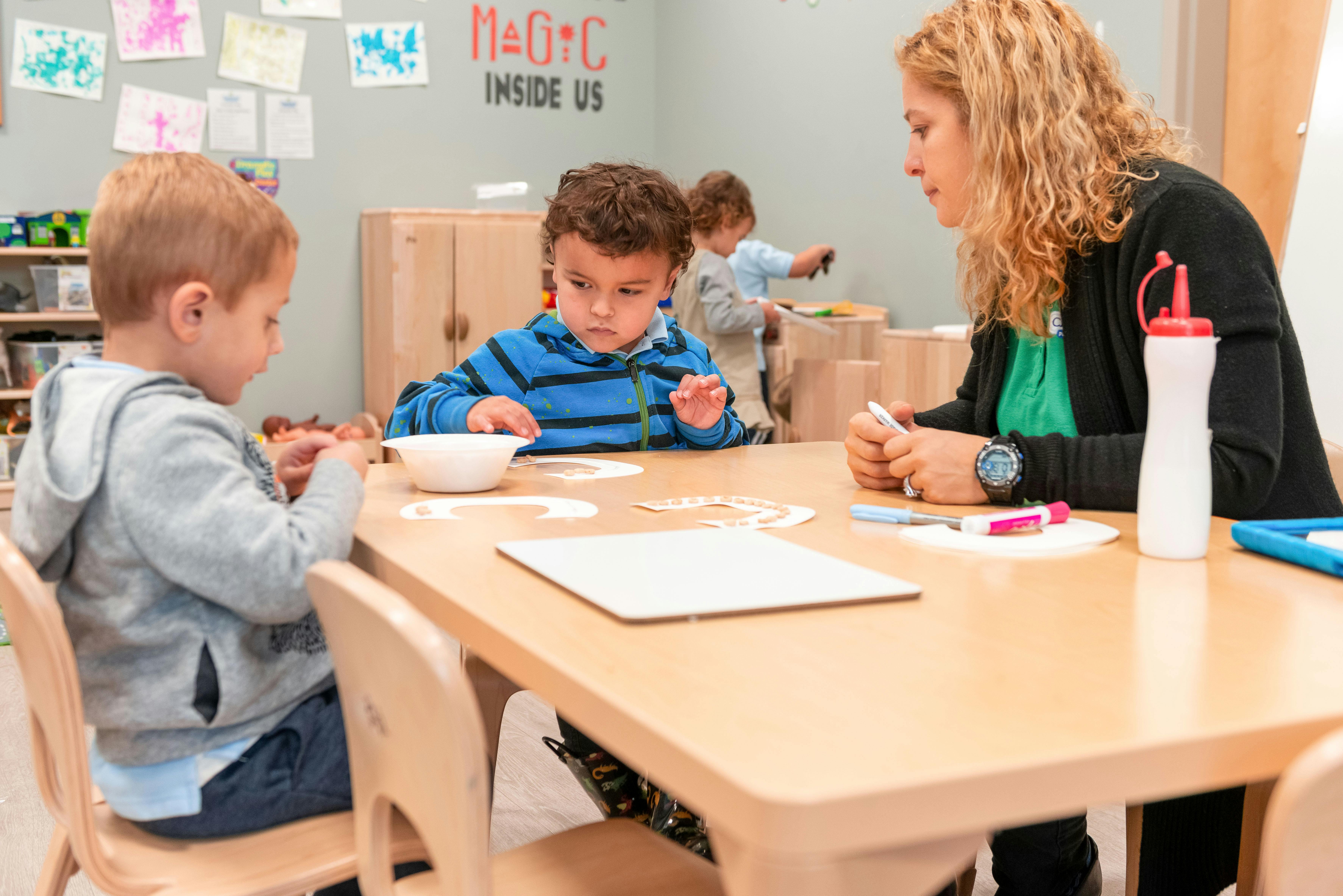 Adult and two children at a table in a classroom