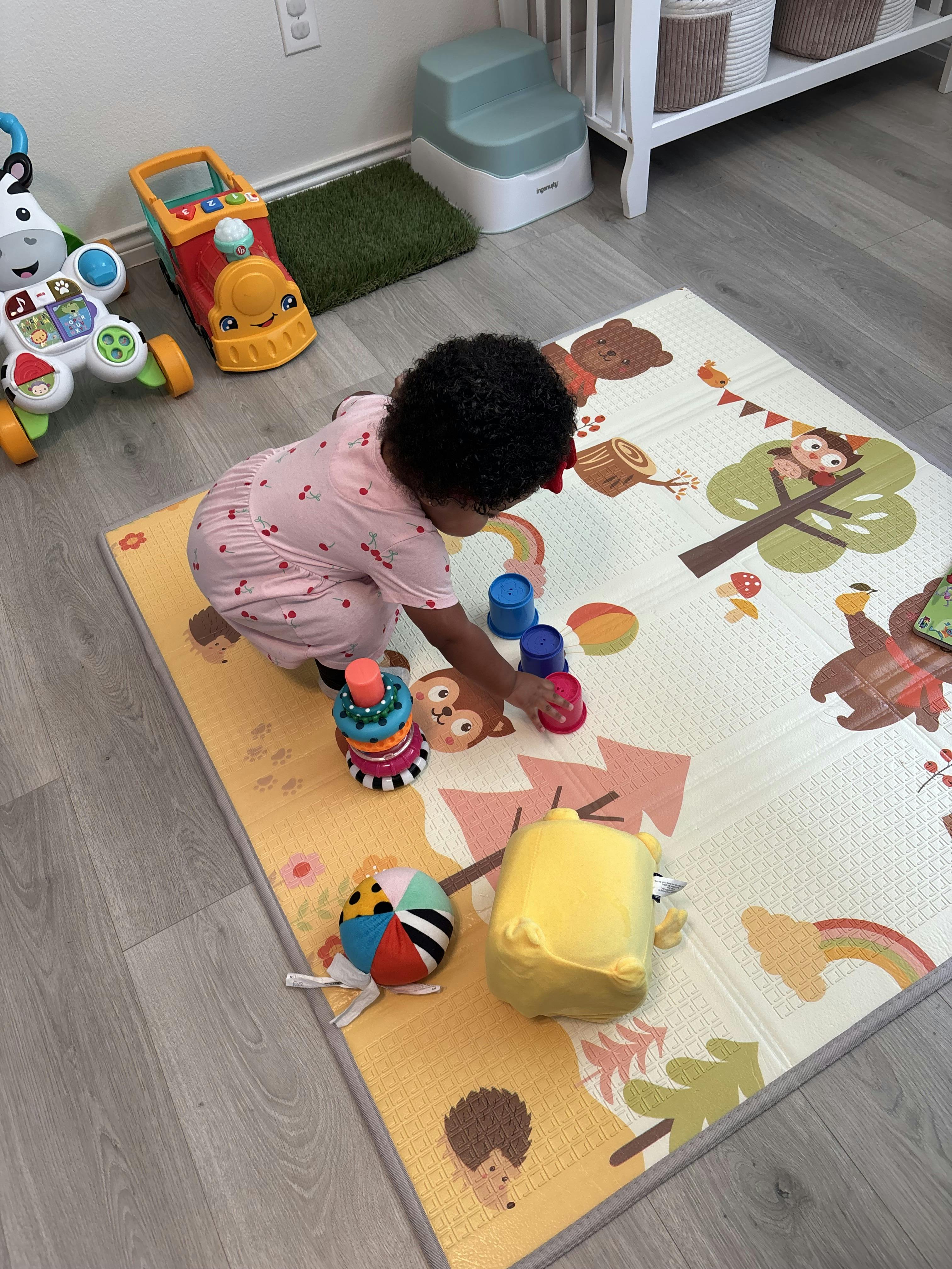 Child playing with stacking cups on a decorated floor mat