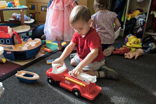 Child playing with a toy fire truck on the floor
