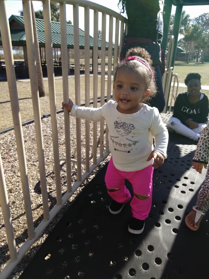 Child standing on a playground structure, holding onto a railing
