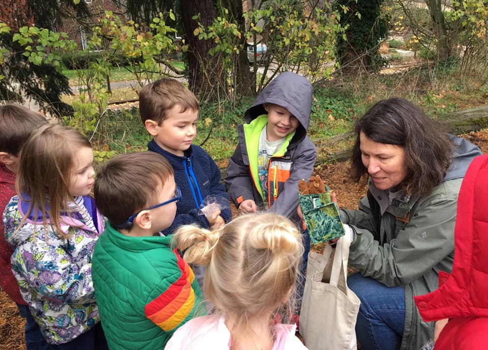 Adult showing an object to a group of children outdoors