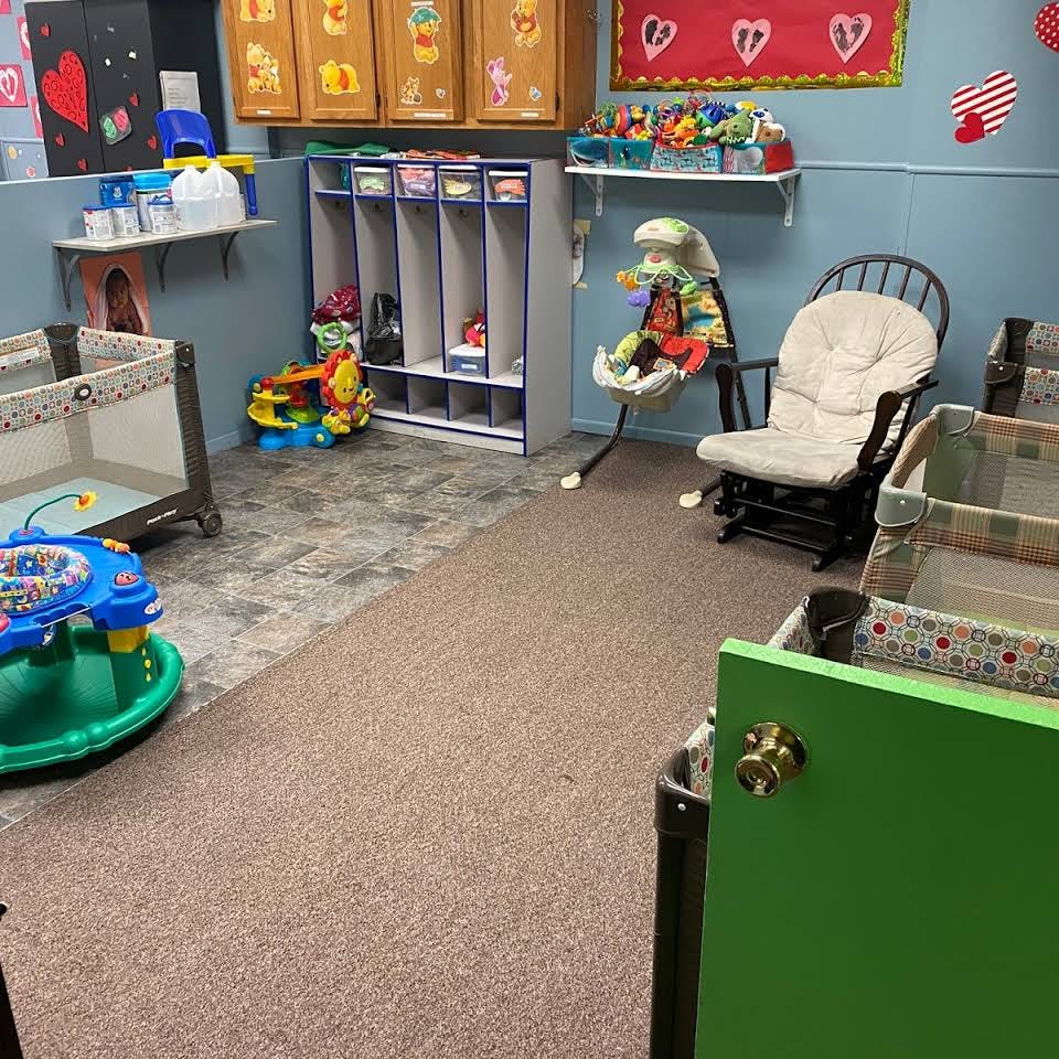 Daycare room with cribs, baby bouncer, and rocking chair
