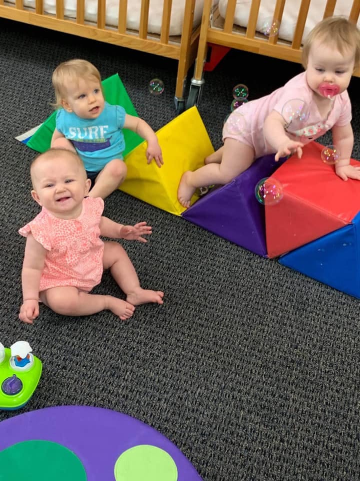 Three babies playing on colorful soft blocks