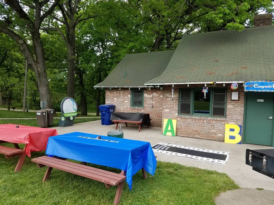 Picnic tables with red and blue tablecloths outside a brick building