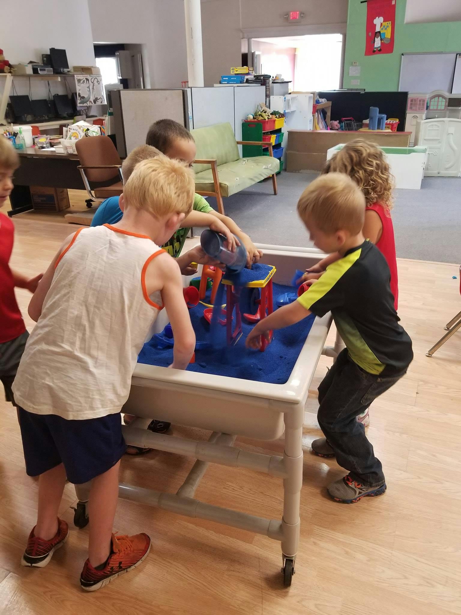 Children playing at a water table in a classroom