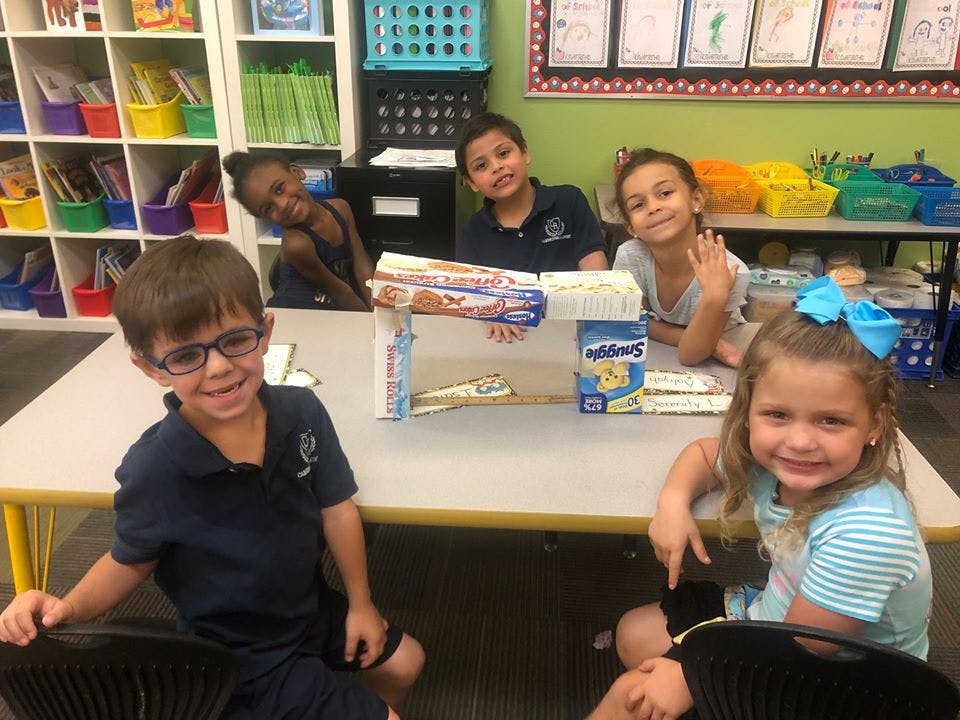 Children sitting at a table with a craft project made from boxes