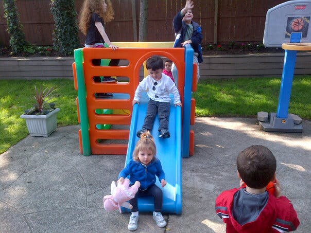 Two children on a slide with other people nearby
