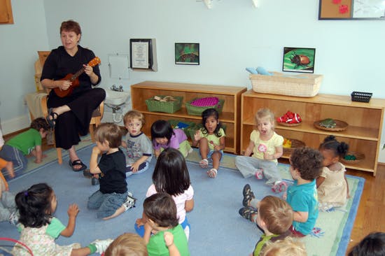 Person playing ukulele for children in a classroom