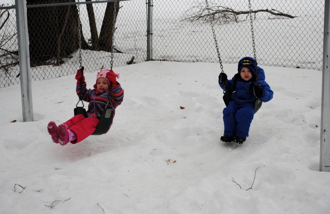 Two children on swings in the snow