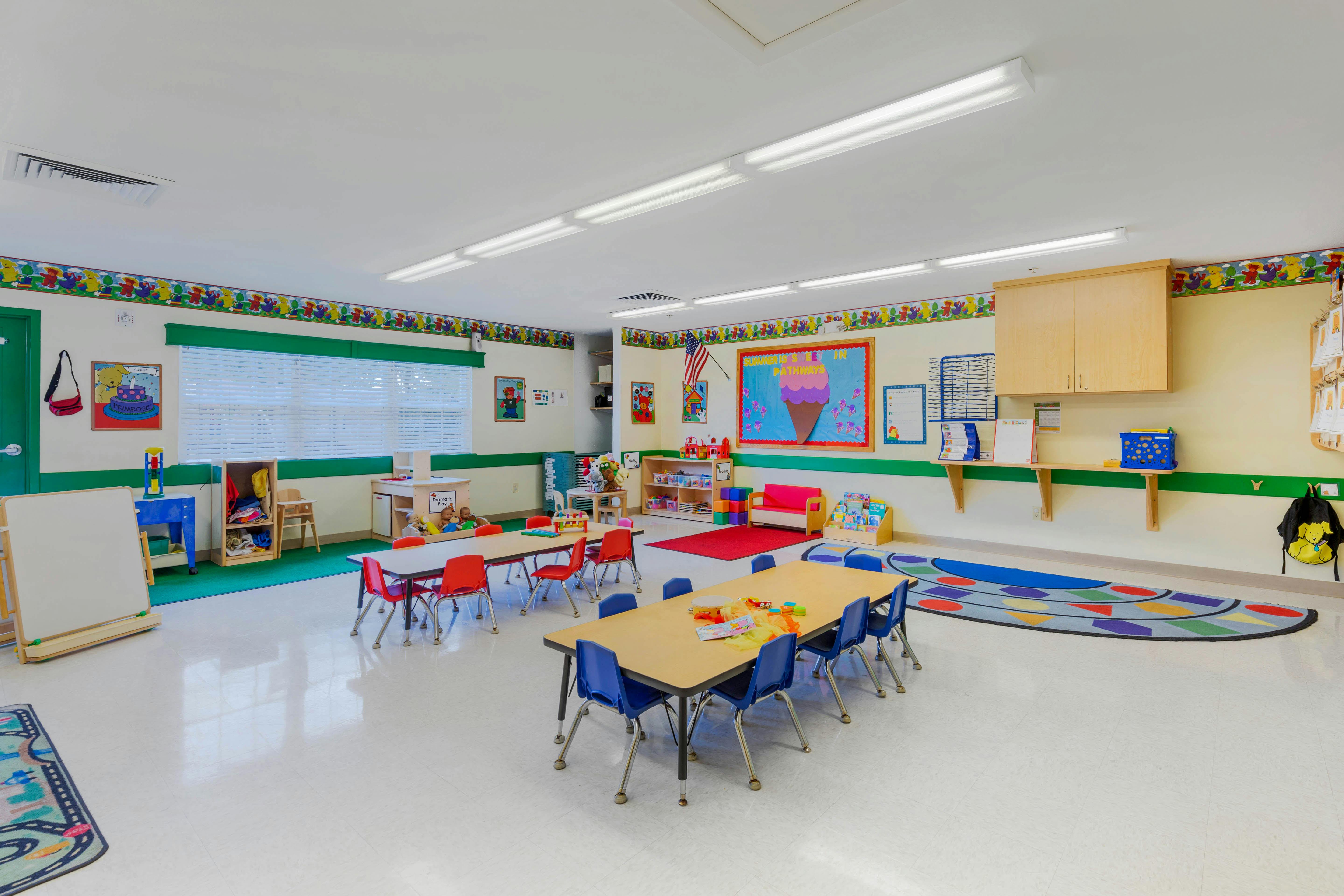 An empty classroom with small tables and chairs, colorful decorations on the walls