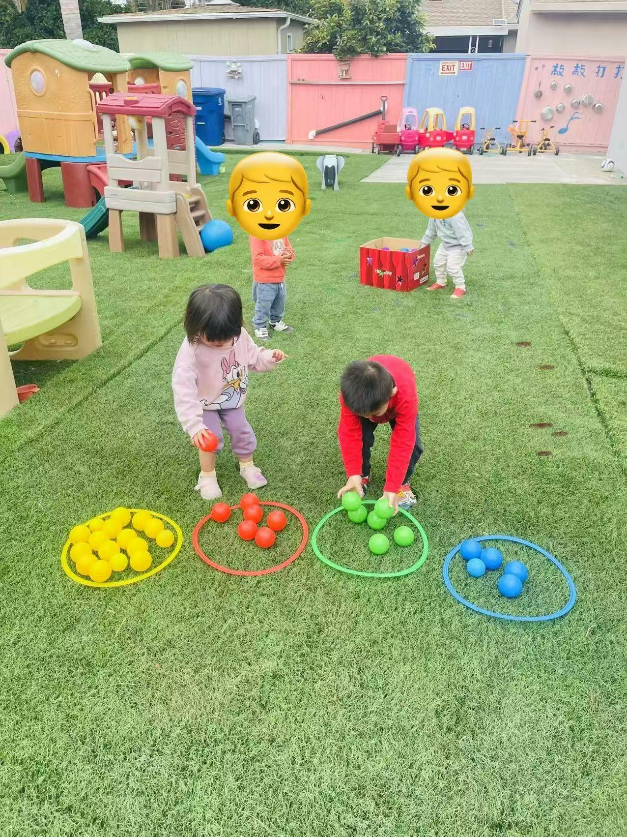 Children playing with balls and hoops on artificial grass