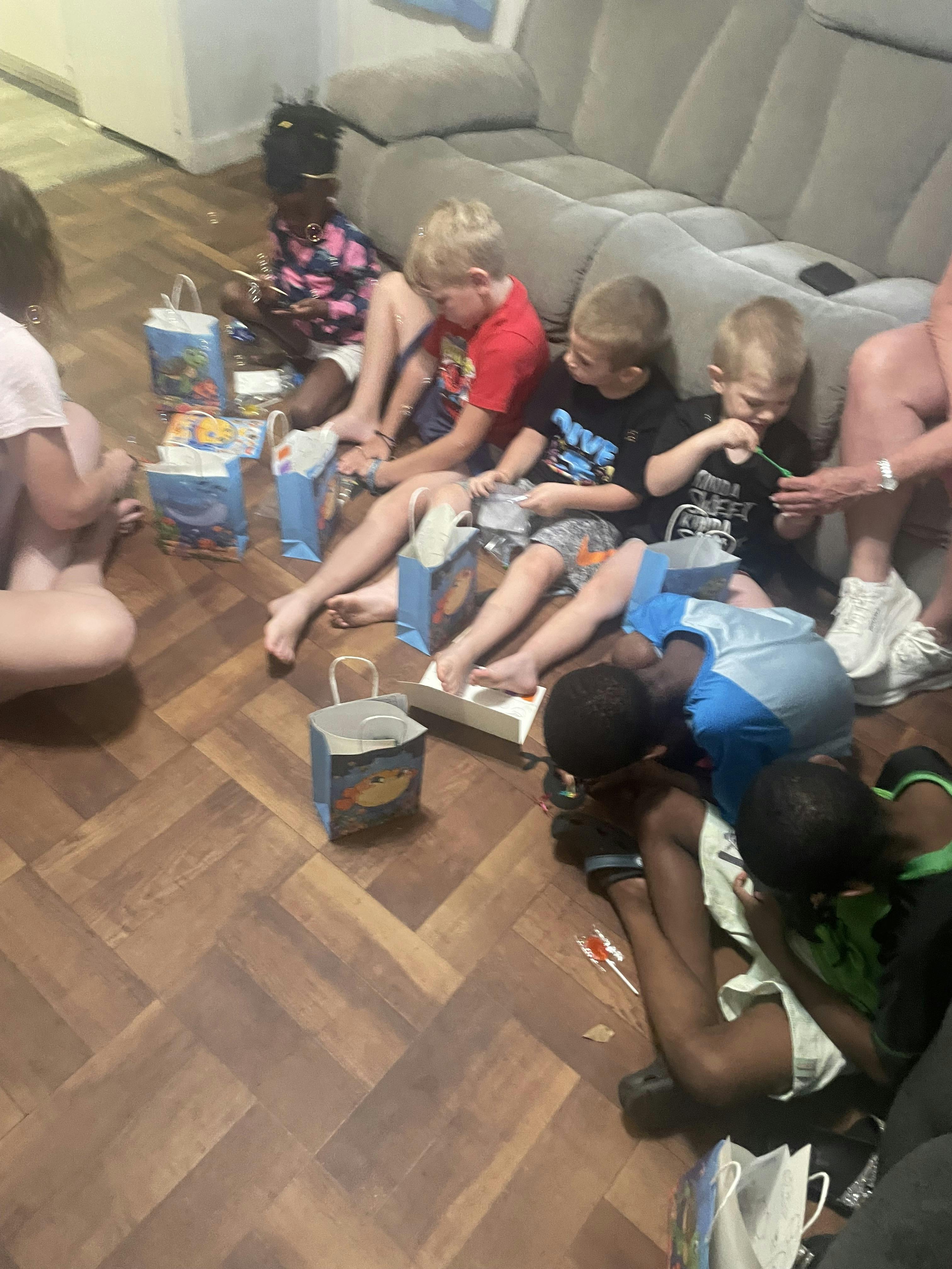 Group of children sitting on a living room floor with gift bags