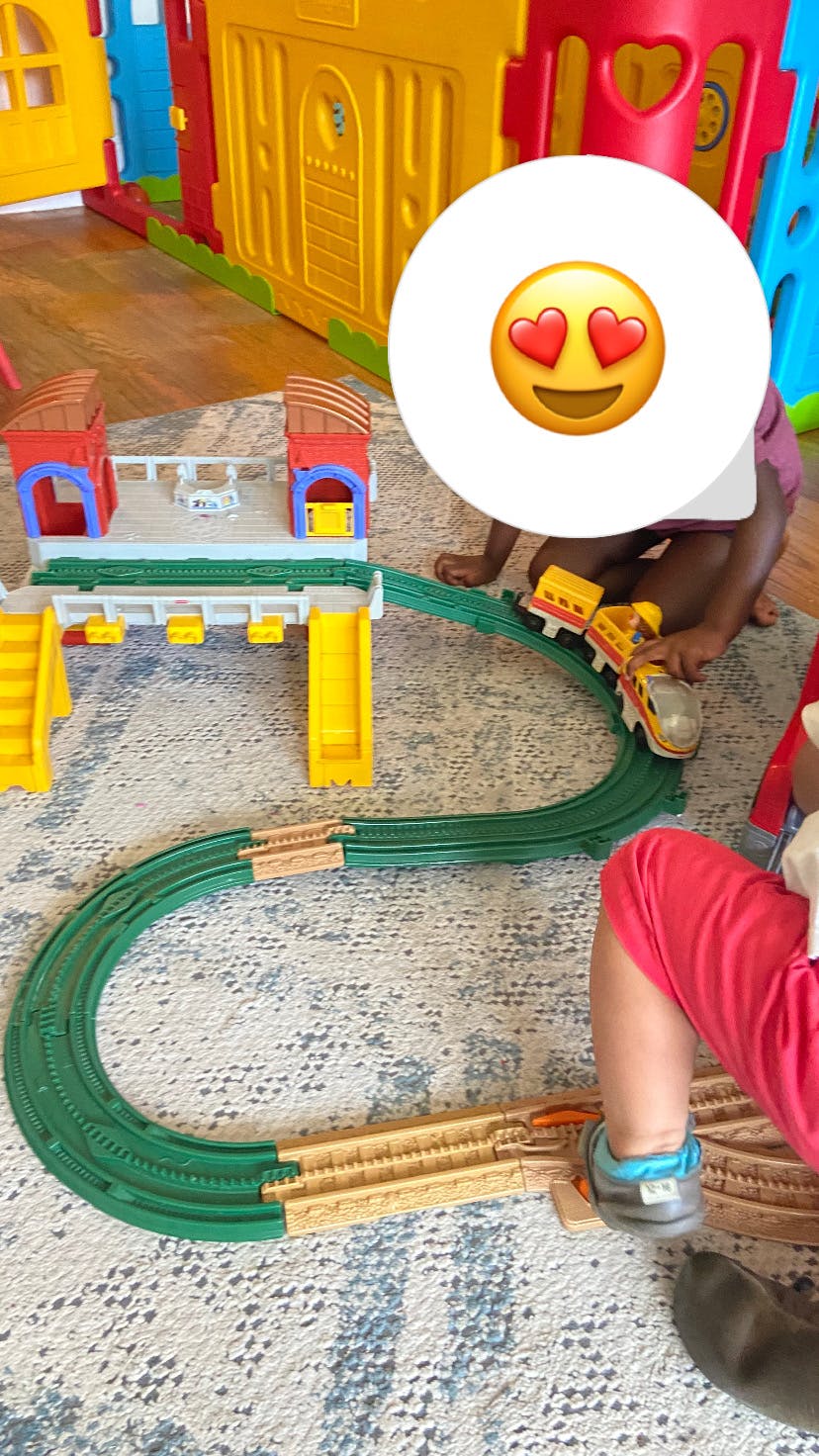 Child playing with a toy train set on a rug