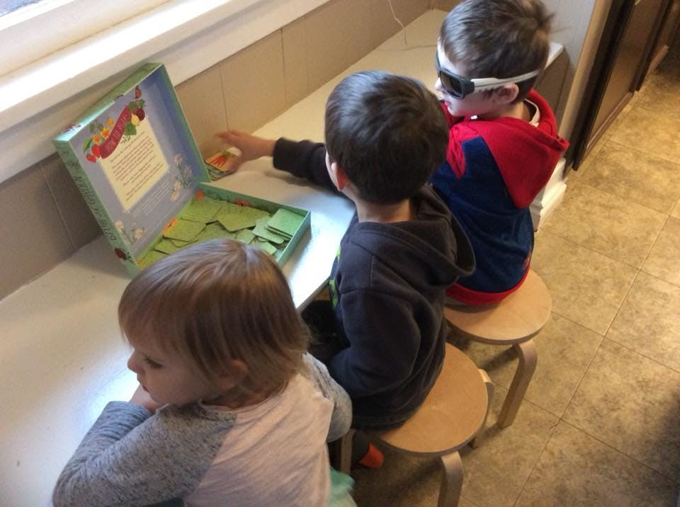 Three children sitting at a table with a game