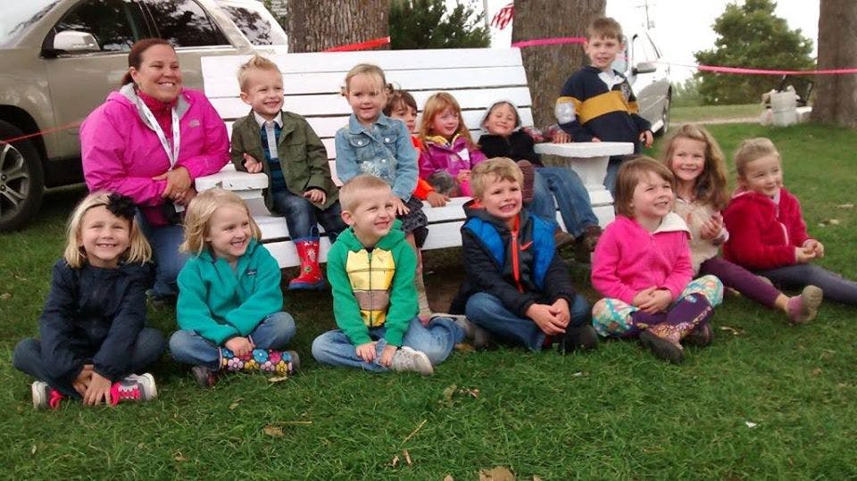 Adult and children sitting on a bench and grass outdoors on the grass outdoors