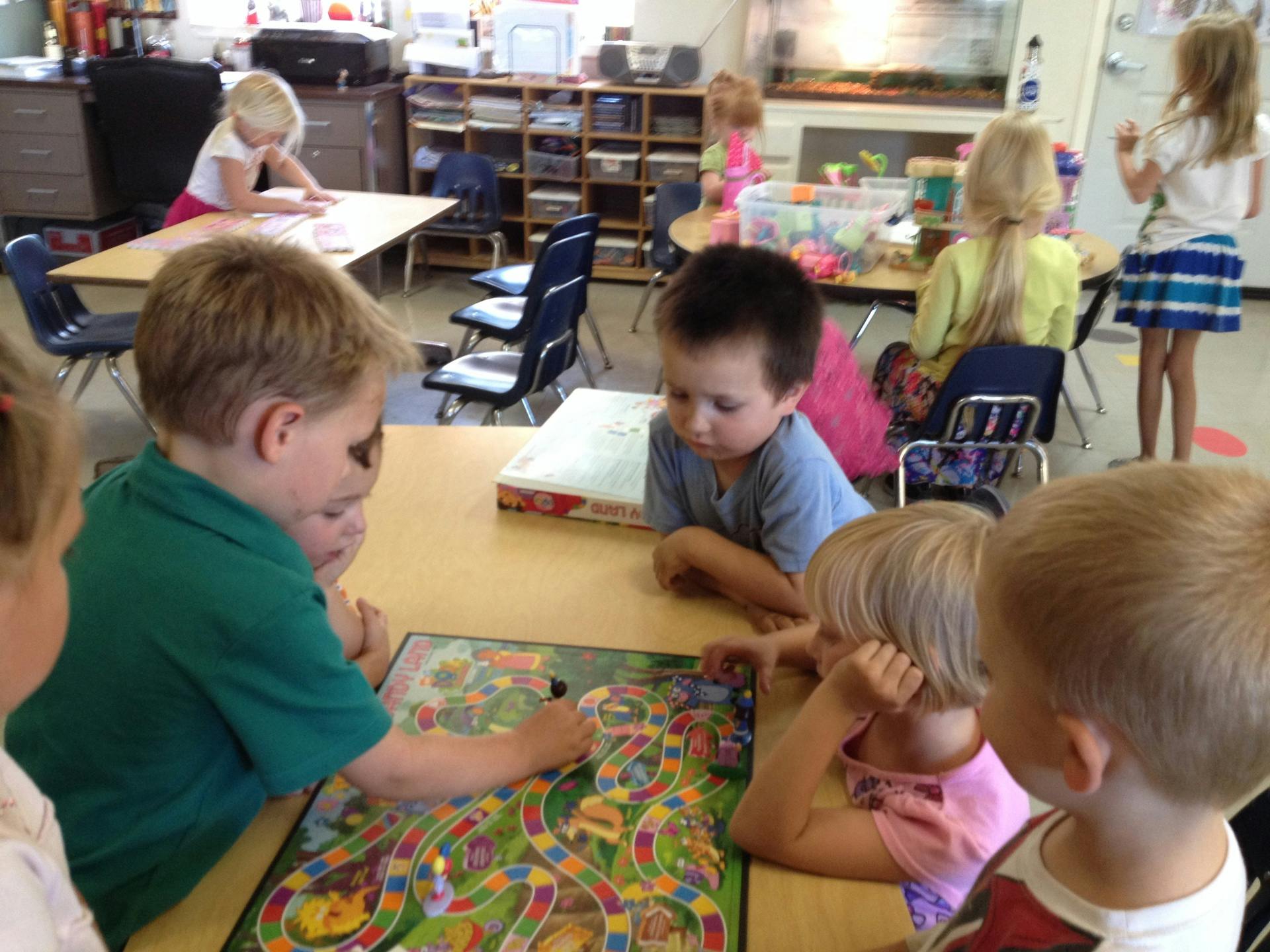 Children playing a board game at a table in a classroom