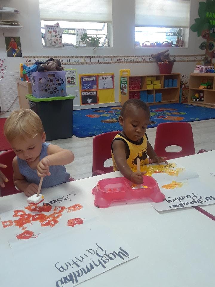 Two children painting with marshmallows in a classroom