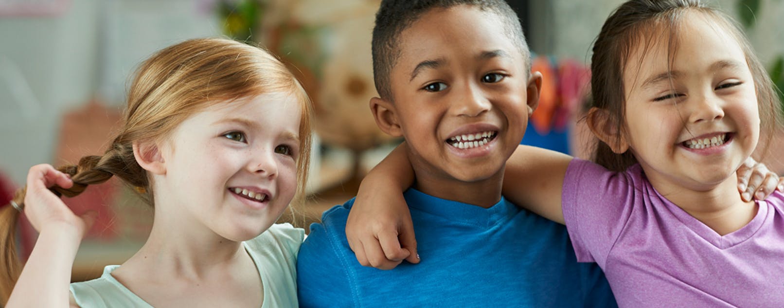 Three children smiling with arms around each other
