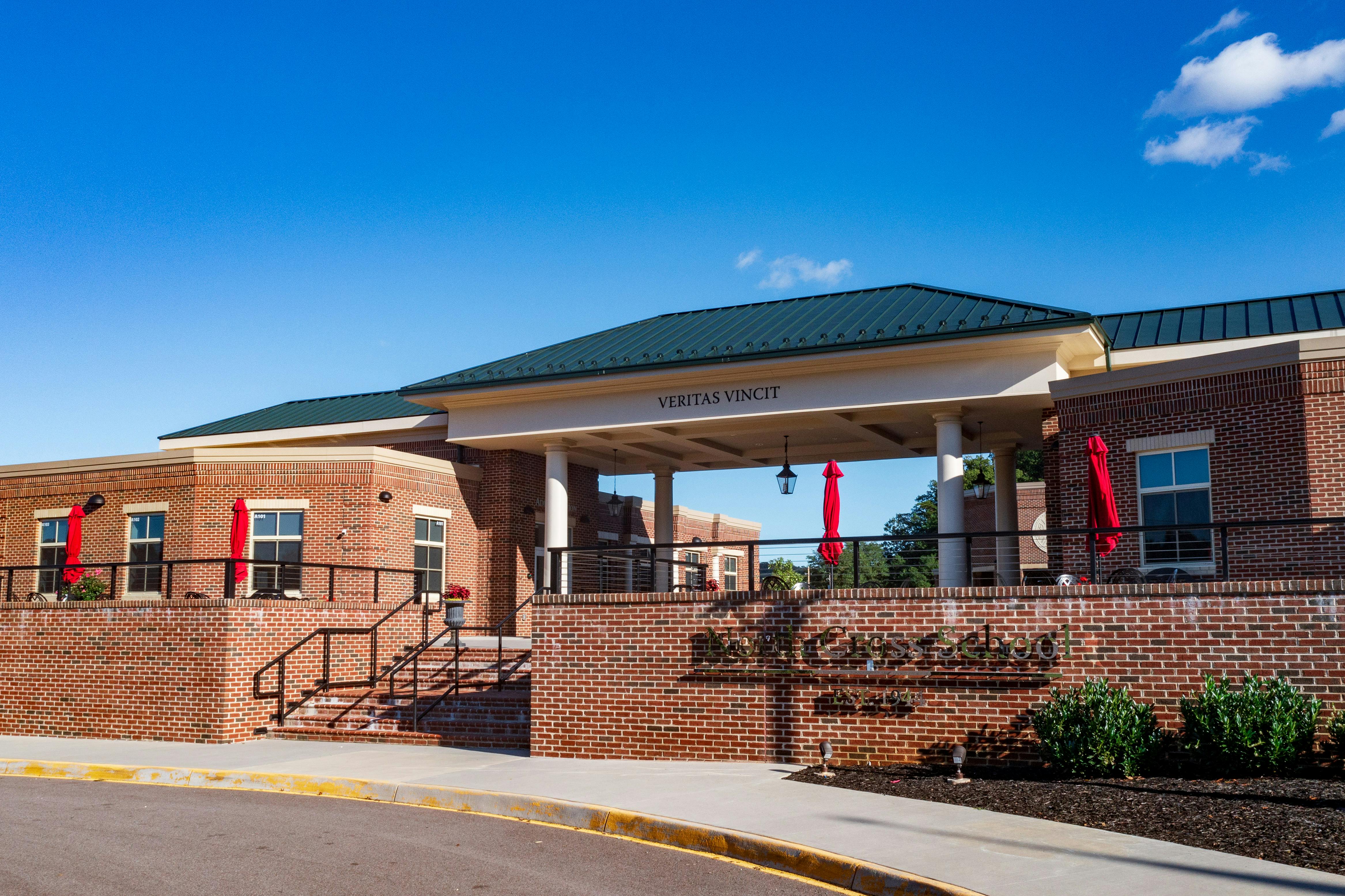 Brick building with a covered entrance and red umbrellas