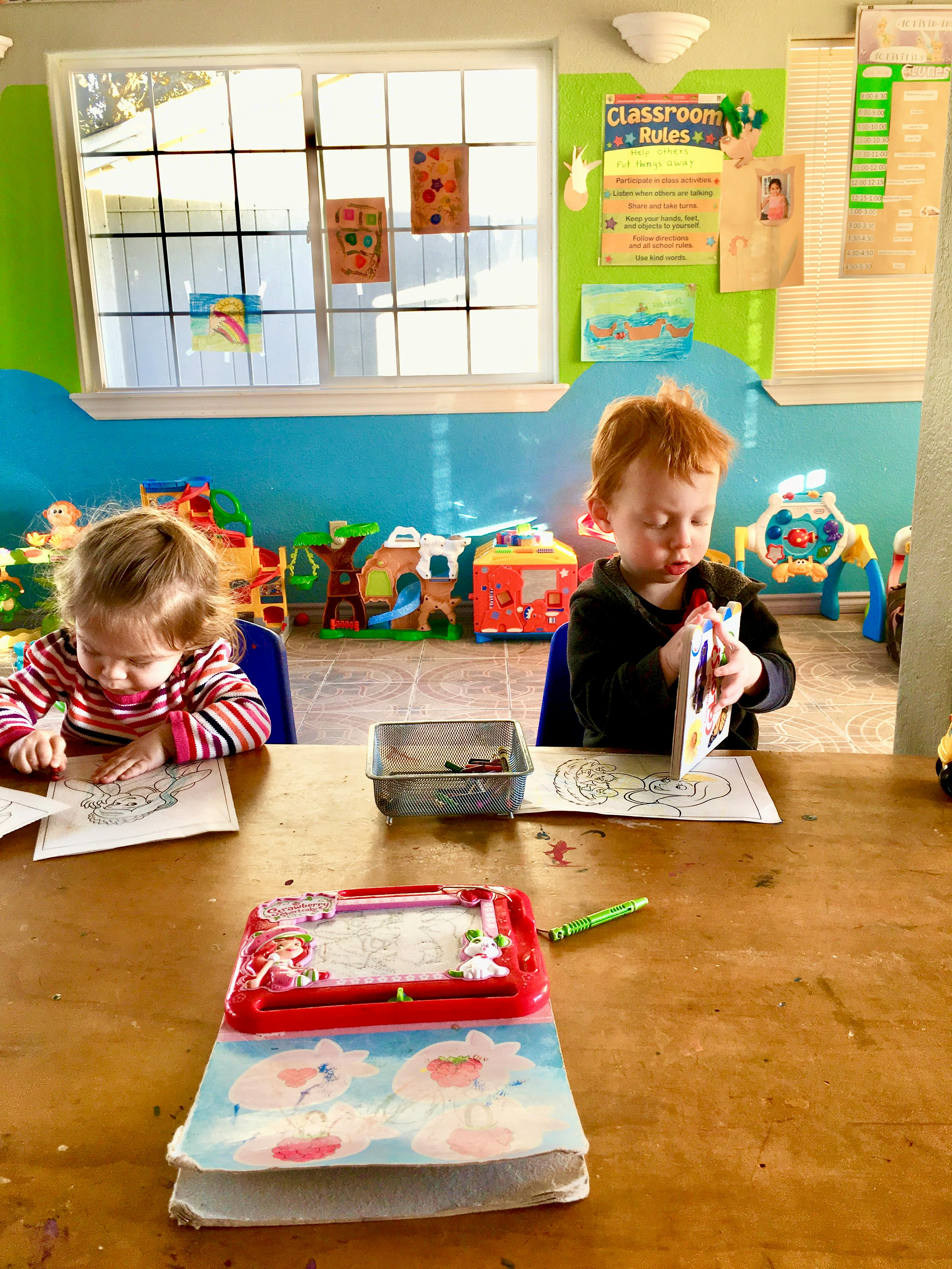 Two children coloring at a table in a classroom