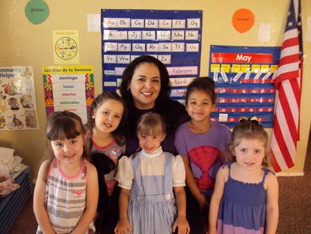Adult and four children posing in a classroom