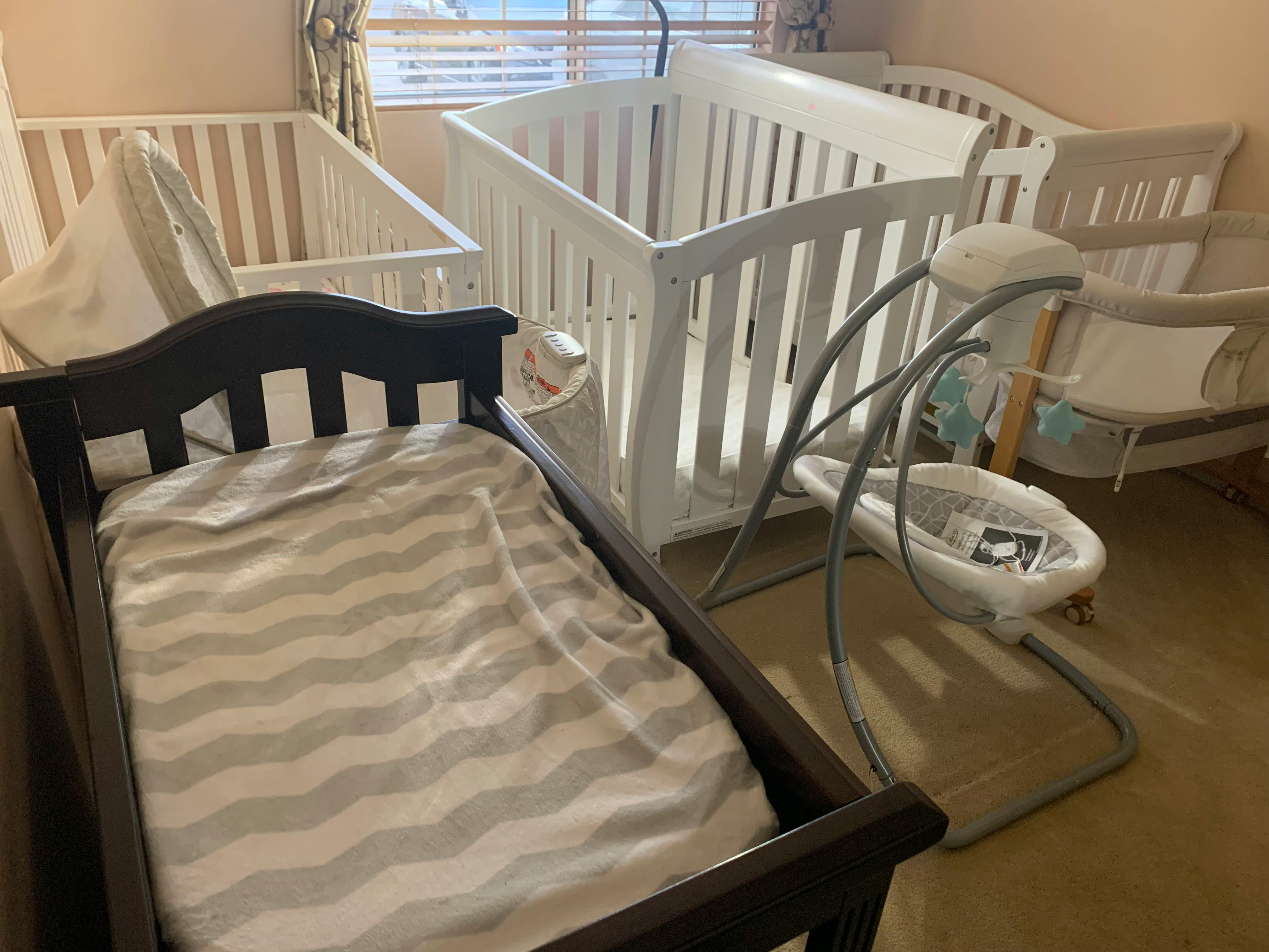 Two cribs and a baby swing in a room