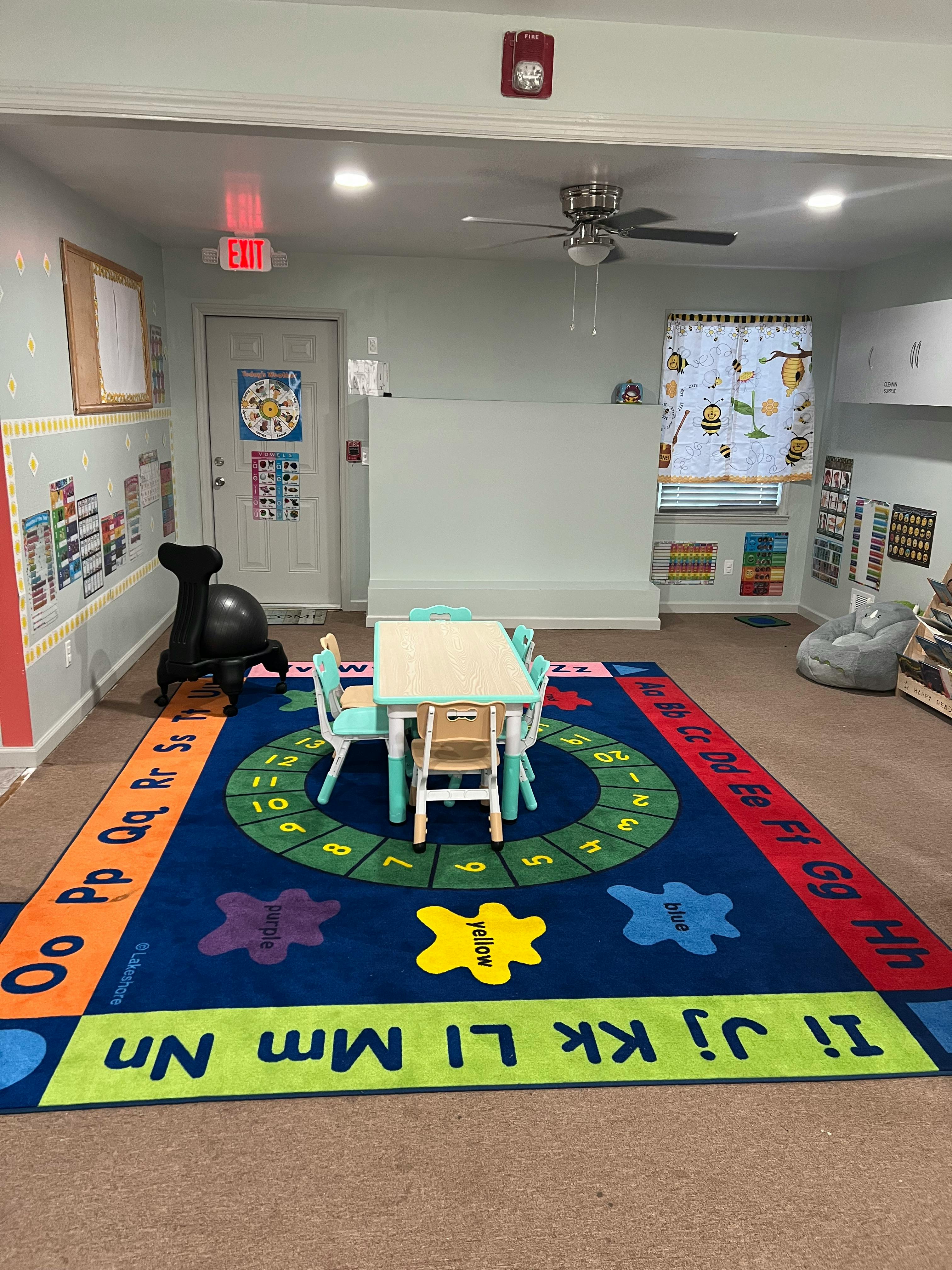Classroom with a small table and chairs on an alphabet rug