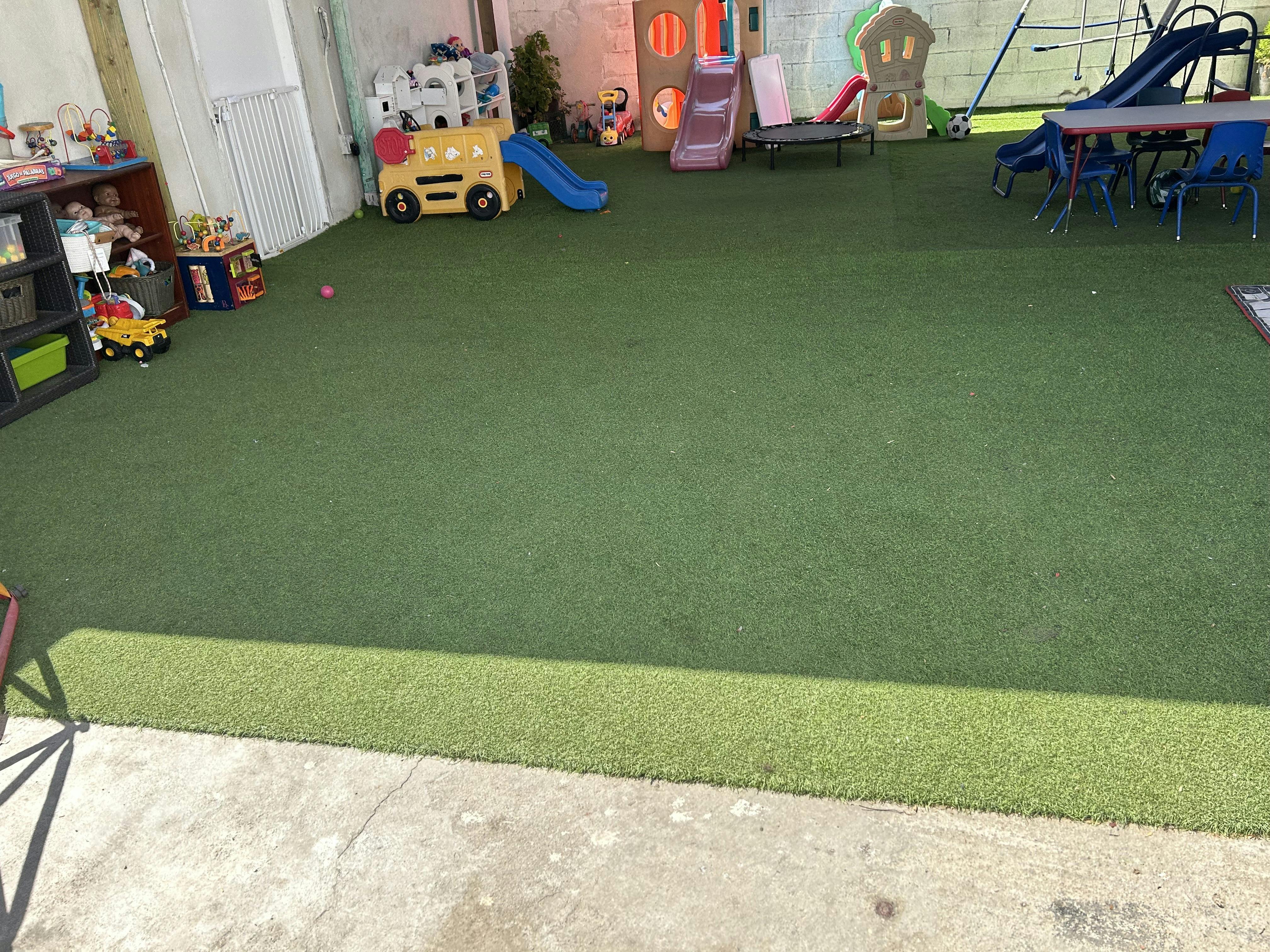 Outdoor play area with artificial turf, slides, and small tables