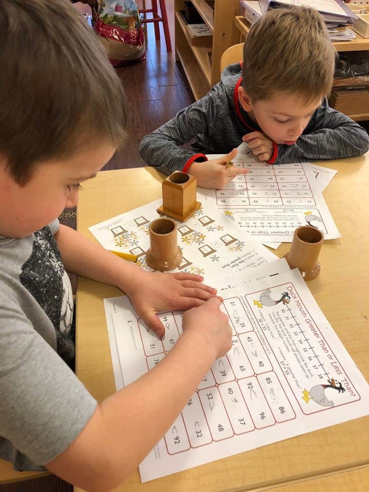 Two children working on worksheets at a table
