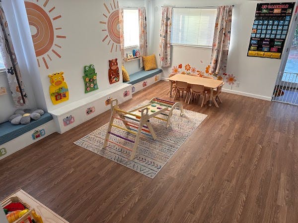 Playroom with a table, chairs, toy shelf, and decorative suns on the wall