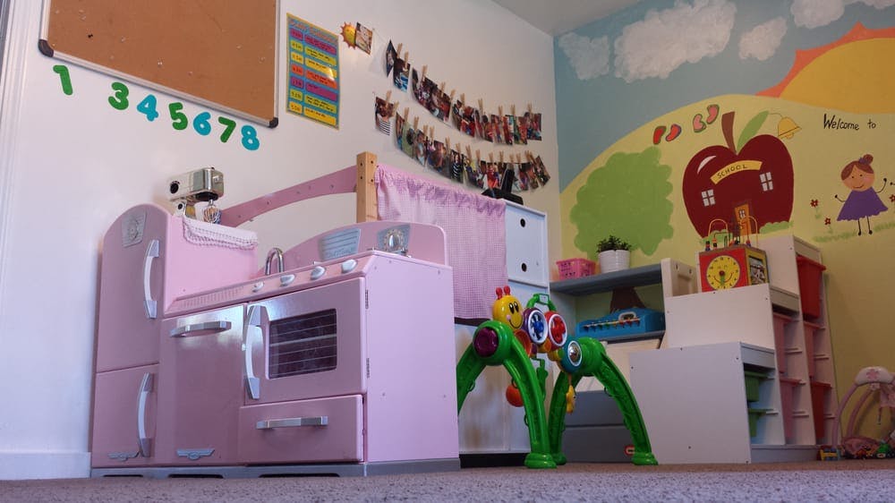 Pink toy kitchen in a child's room with wall murals