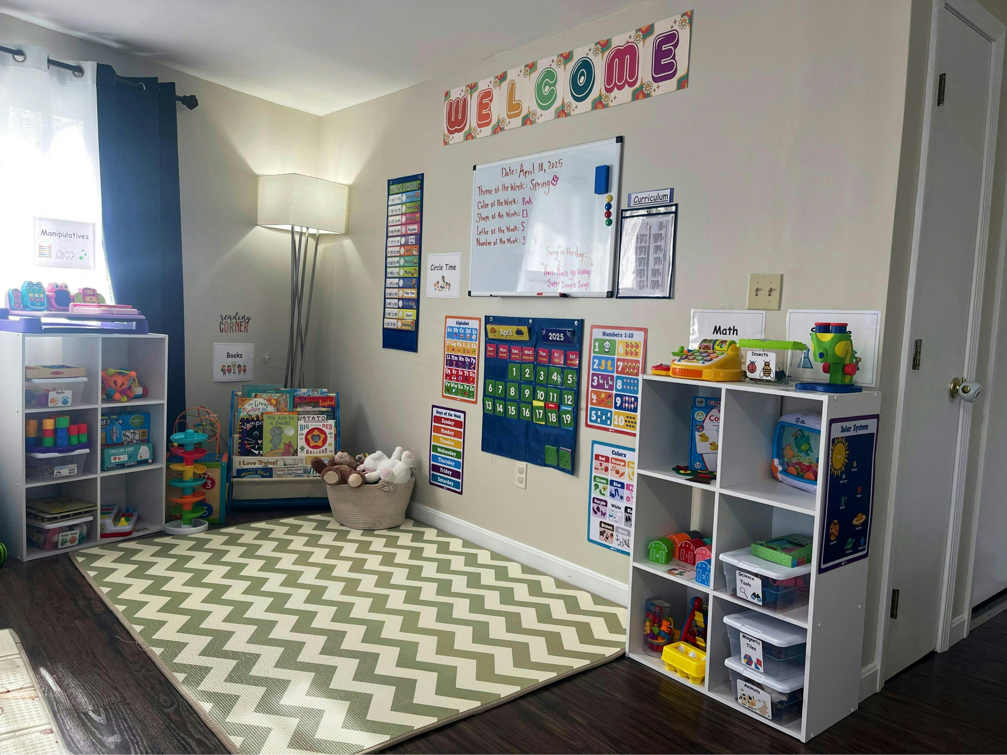 Playroom with a chevron rug, shelves of toys, and educational posters on the wall