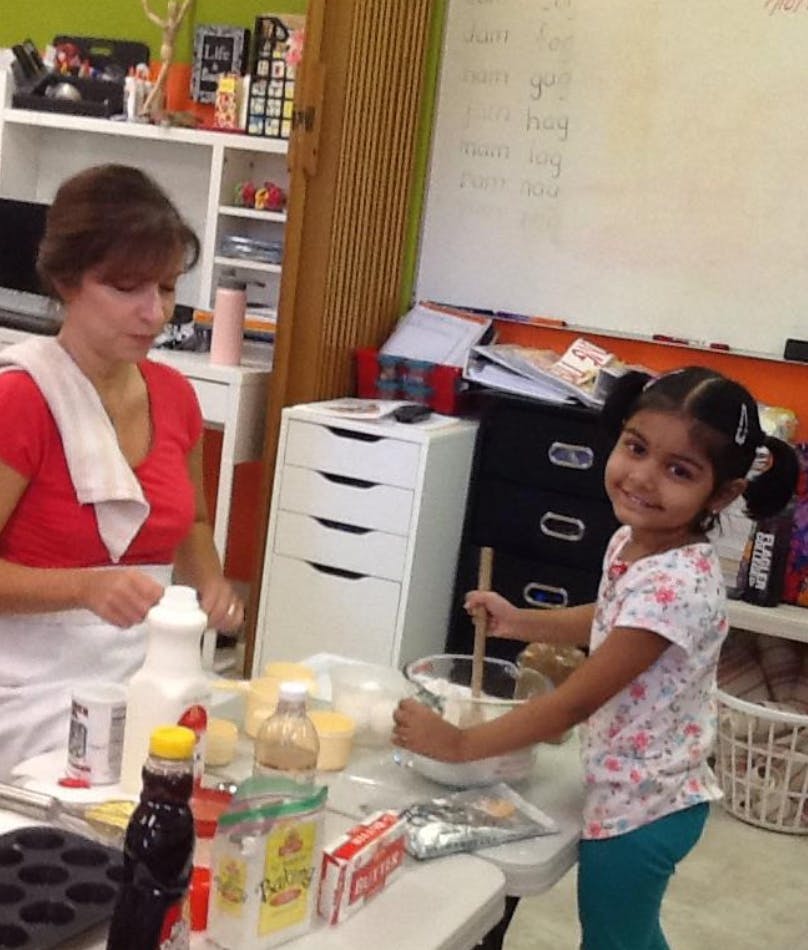 Person and child mixing ingredients in a kitchen