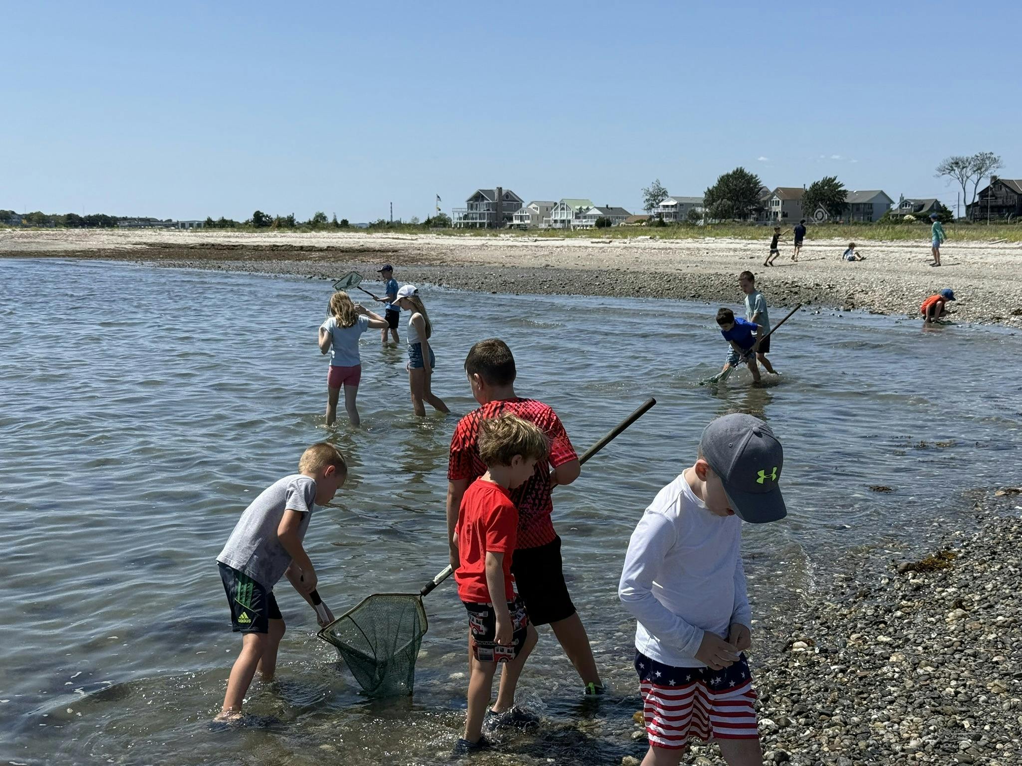 Children wading in shallow water with nets