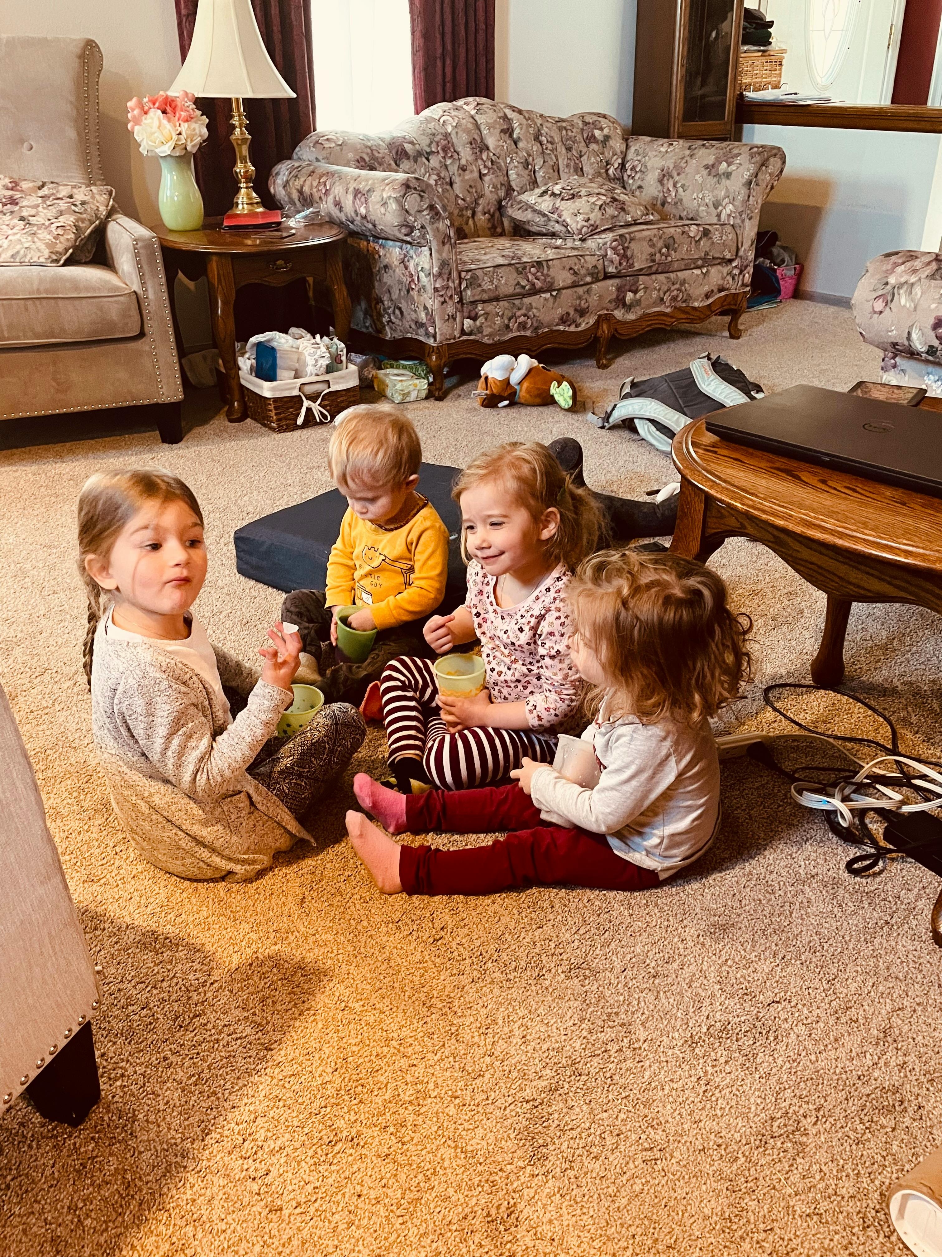 Four children sitting on a carpeted floor