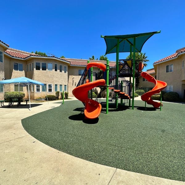 Playground with orange slides and green protective surfacing