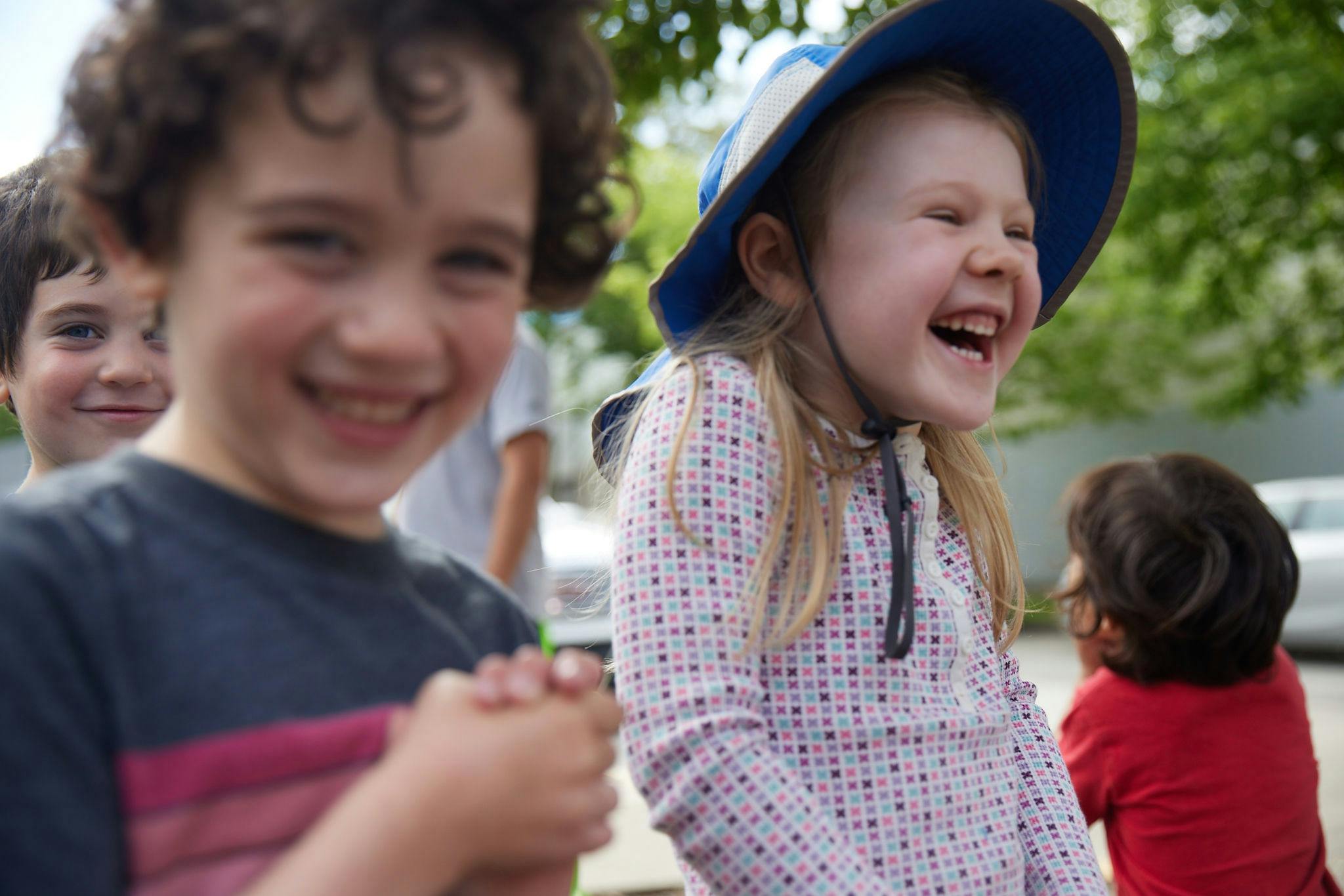 Child in blue hat laughing with other children
