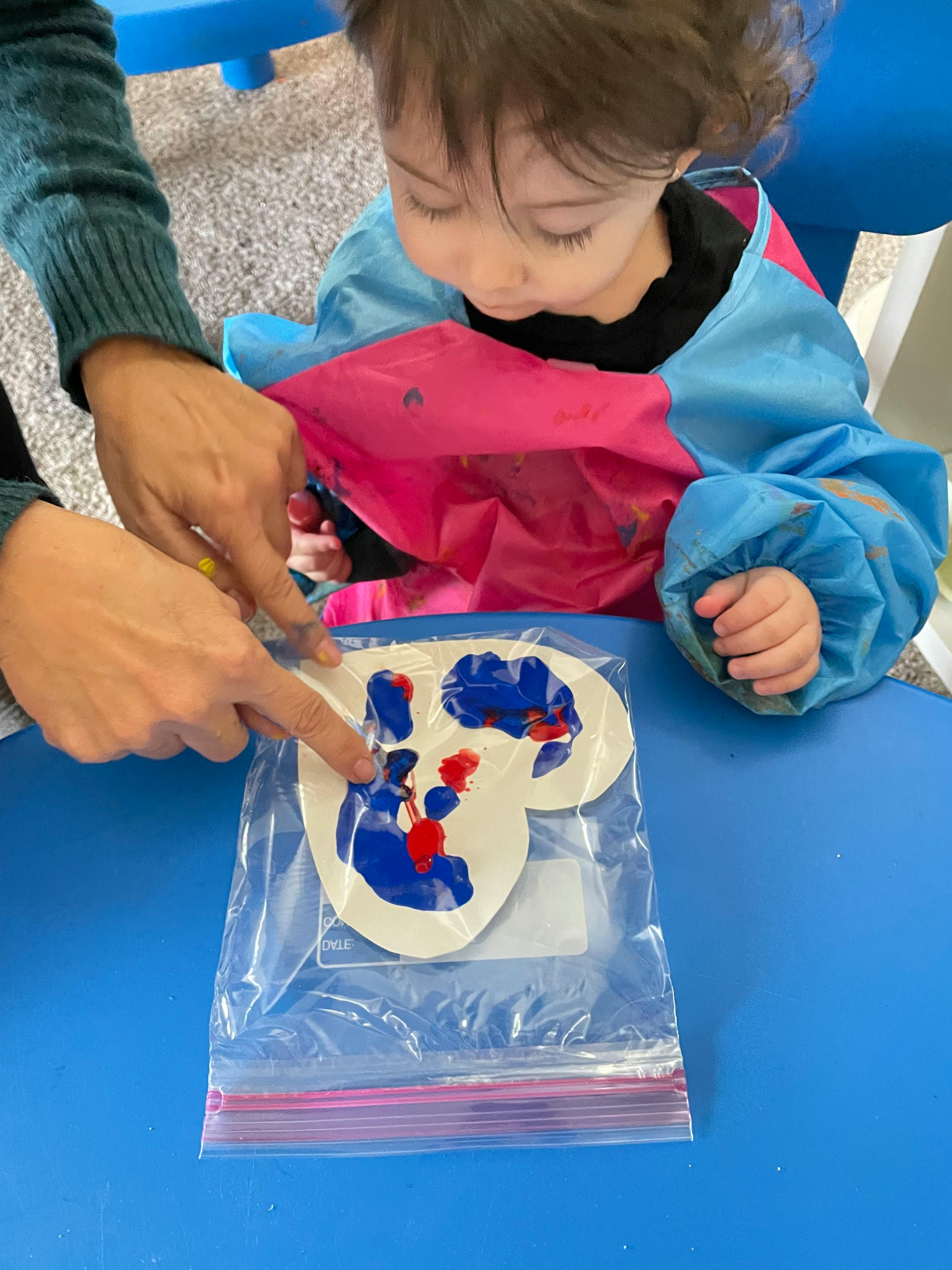 Adult and child doing a paint activity with a plastic bag