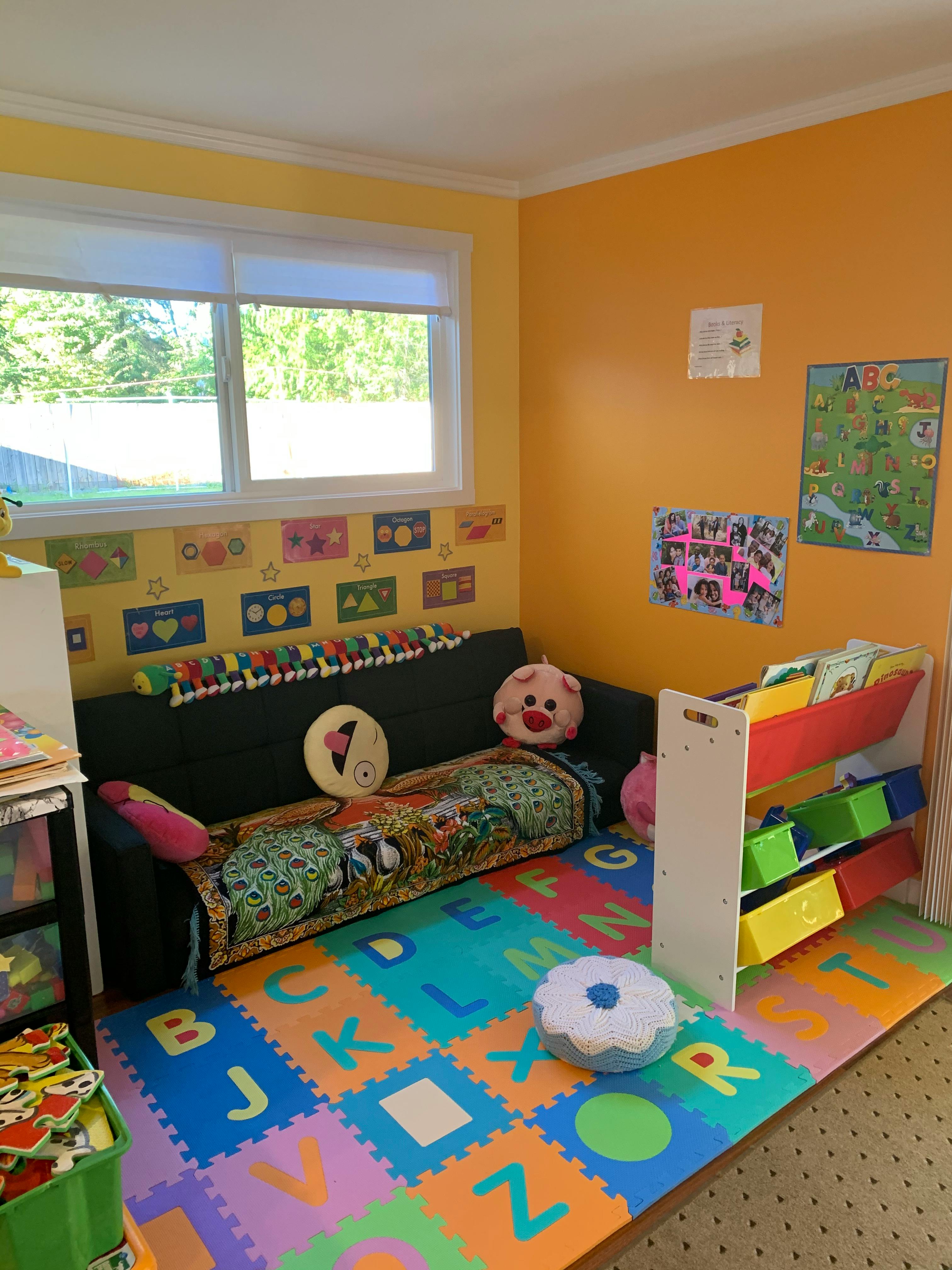 Playroom with a couch, alphabet mat, and toy storage
